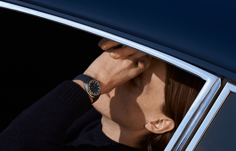 Close-up image of a man wearing a luxury watch, sat inside a car.